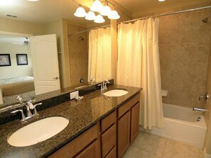 A bathroom with two sinks, a large mirror, and a bathtub. - 8963 Paradise Palms Townhome 4 Bedroom by Florida Star (Kissimmee)