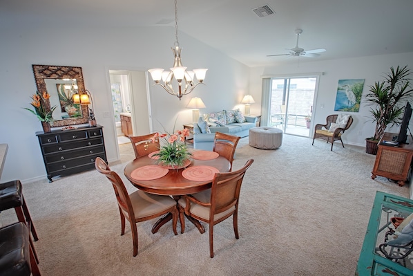 A spacious living room with a dining area, a large mirror, and a ceiling fan.