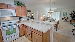 Uma cozinha moderna com armários de madeira, uma ilha central e uma área de jantar com lustre.