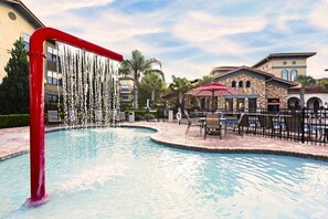 A swimming pool with a red pipe, surrounded by lounge chairs and a stone building with arches. - 904 Bella Piazza Condo 4 Bedroom by Florida Star (Davenport)