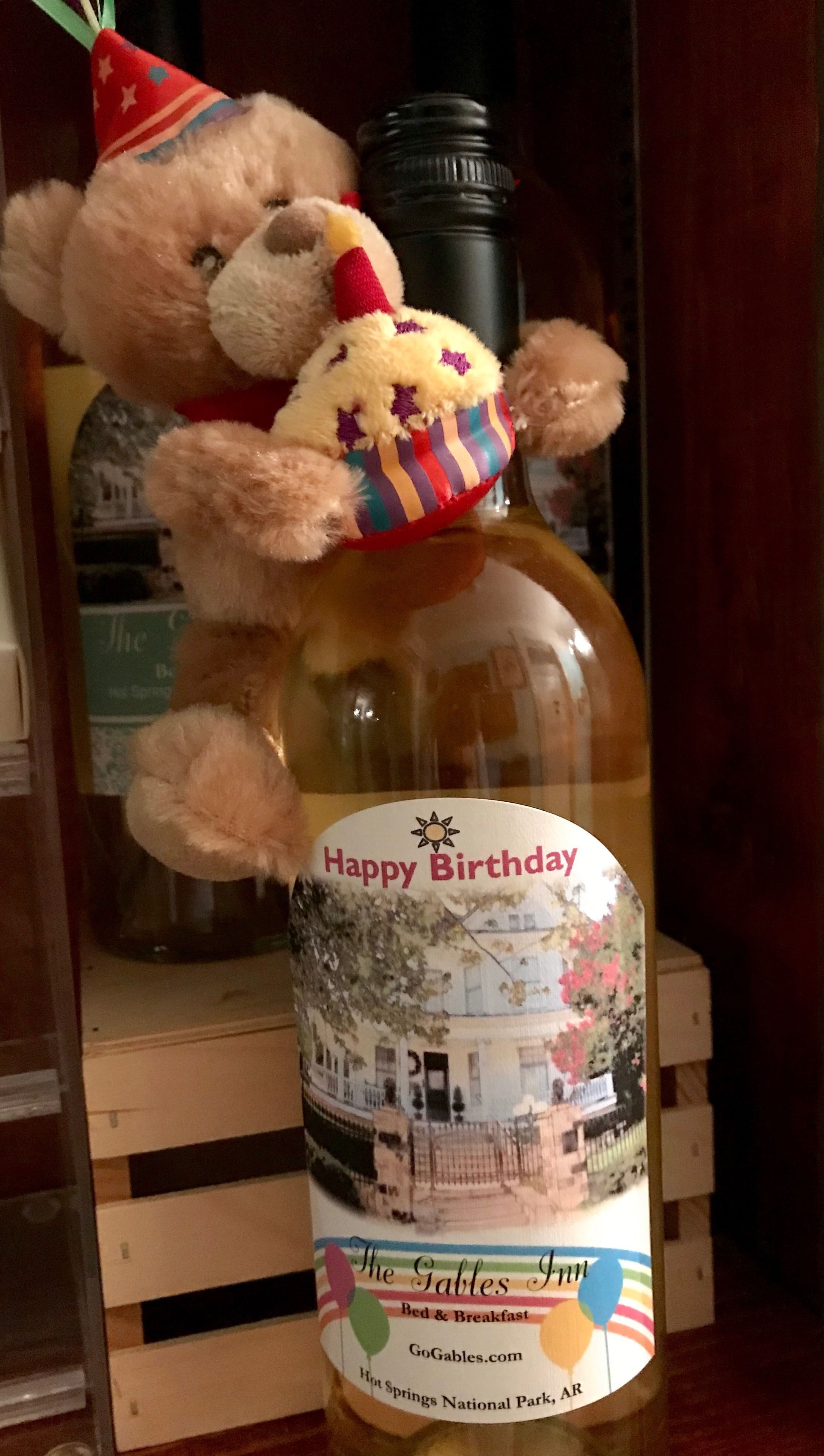 Ampolla amb una etiqueta que diu "Felicitats" i "The Tables Inn Bed & Breakfast", amb una imatge floral i d'una casa.
