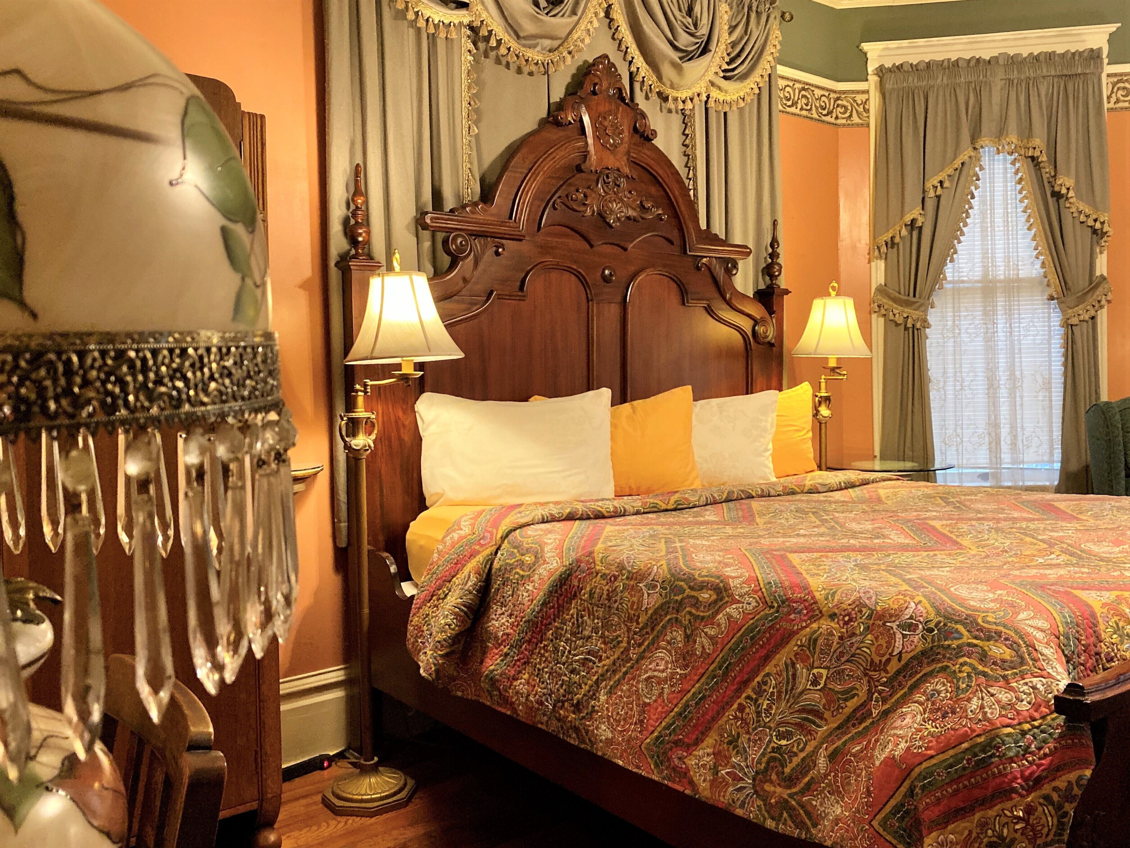 A traditional bed with a wooden headboard, two bedside lamps, and a patterned bedspread.