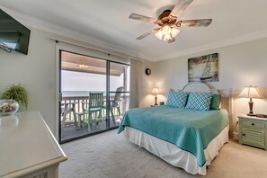 A bedroom with a large bed, a ceiling fan, a view of the ocean through a sliding door, and a painting on the wall. - Anchorage Abode II A02 2 Bedroom Condo by Anchorage (Myrtle Beach)