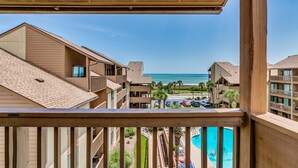 Une vue depuis un balcon donnant sur une piscine et une plage.