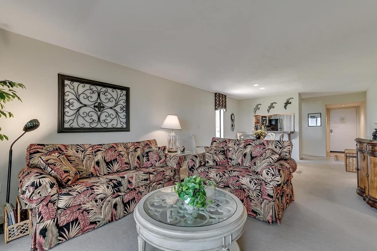A living room with a sofa, a glass coffee table, and a lamp.