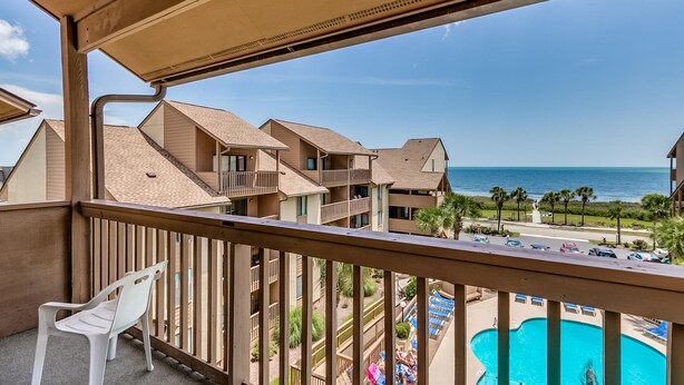 A balcony with a view of a pool and a resort area, including multiple buildings and a clear sky. - Anchorage Abode I A02 2 Bedroom Condo by Anchorage (Myrtle Beach)
