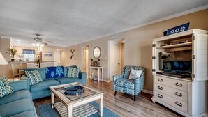 A living room with a sofa, armchair, coffee table, and a cabinet with a television. - Anchorage Abode I A02 2 Bedroom Condo by Anchorage (Myrtle Beach)