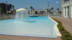 A swimming pool with a water fountain, surrounded by a brick walkway and palm trees. - Ariel Dunes I 3 Bedroom Apartment by BnD (Miramar Beach)