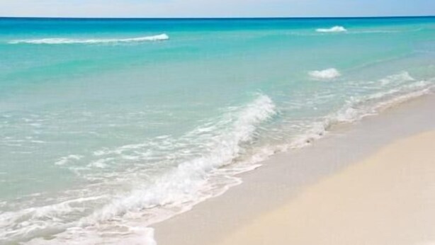 Una playa con agua turquesa cristalina y olas suaves.