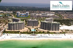 Ein Resort mit drei kreisförmigen Gebäuden, einem zentralen Pool und einem Strand.