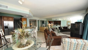 A spacious living area with a glass dining table, a brown sofa, and a patterned armchair. - St Croix at Silver Shells 3 Bedroom Apartment by BnD (Destin)