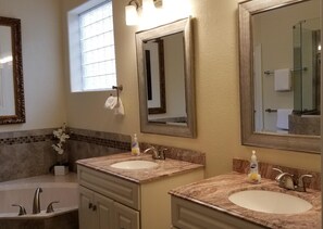 Un baño con dos lavamanos, una bañera y una ventana.