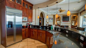 Una cocina moderna con un refrigerador de acero inoxidable, armarios de madera y una isla curva con pileta.