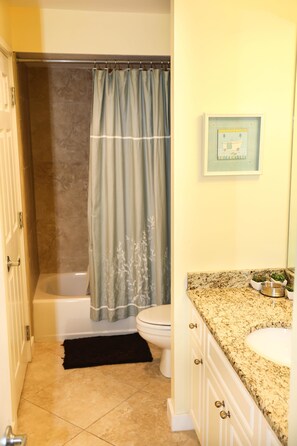 Une salle de bain avec une baignoire, des toilettes, un lavabo et un tableau encadré au mur.