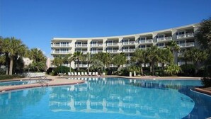A hotel with a large pool, multiple balconies, and palm trees.