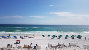 A beach with rows of beach chairs and umbrellas, a sandy shore, and the ocean in the background. - 3rd Floor SeaDunes 3 Bedroom Apartment by BnD (Fort Walton Beach)