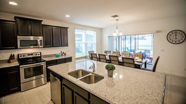 A modern kitchen with granite countertops, stainless steel appliances, and a dining area with a view.