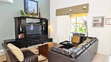 Una sala de estar con mueble multimedia negro, sofá de cuero y una mesa de centro.