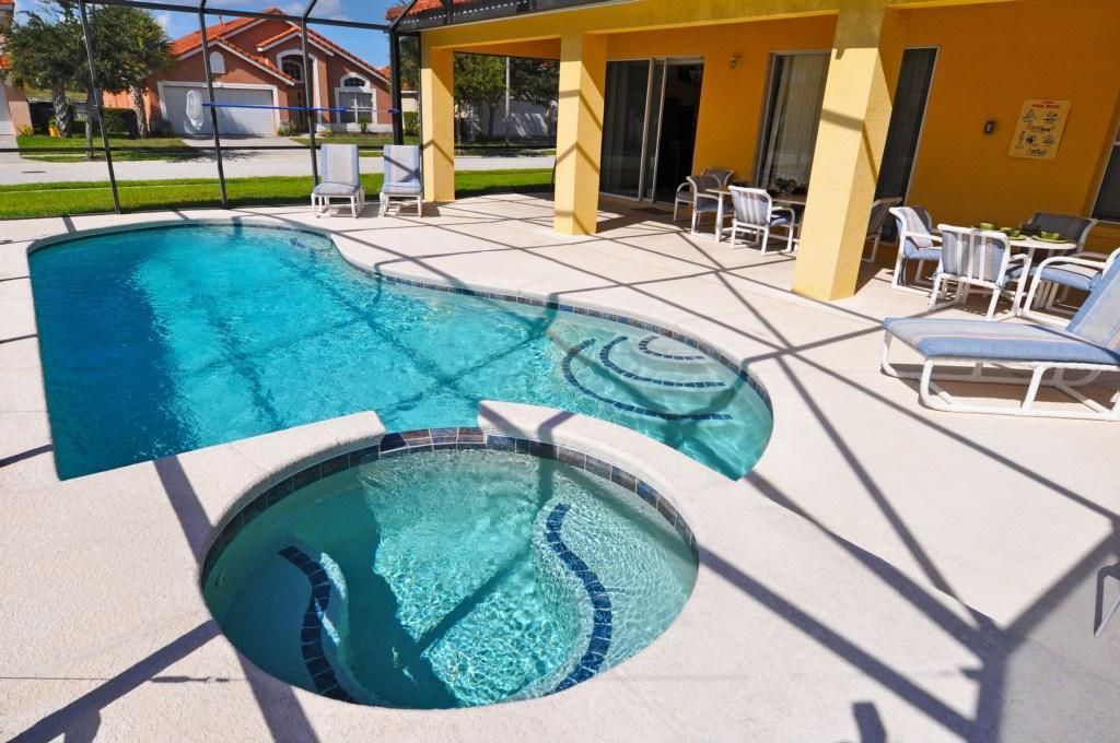 Una piscina con una sección hundida, rodeada de sillones de descanso y un porche cubierto.