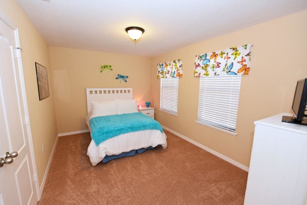 A bedroom with a bed, a nightstand, a dresser, and butterfly wall decorations.