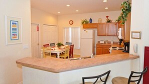 A kitchen with a central island, wooden cabinets, and a dining area with chairs.