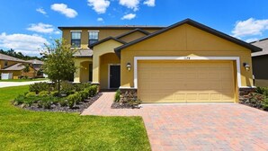 A two-story house with a yellow facade, a garage, and a well-maintained lawn.
