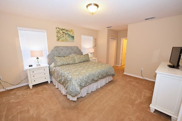 A bedroom with a bed, nightstands, a TV, and a painting on the wall.