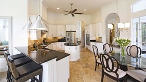 A spacious kitchen with white cabinets, a central island, and a dining area with chairs.
