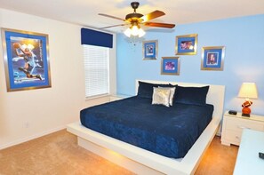 A bedroom with a bed, a ceiling fan, a nightstand, and framed pictures on the wall. - 1299 The Dales House 7 Bedroom by Florida Star (Davenport)