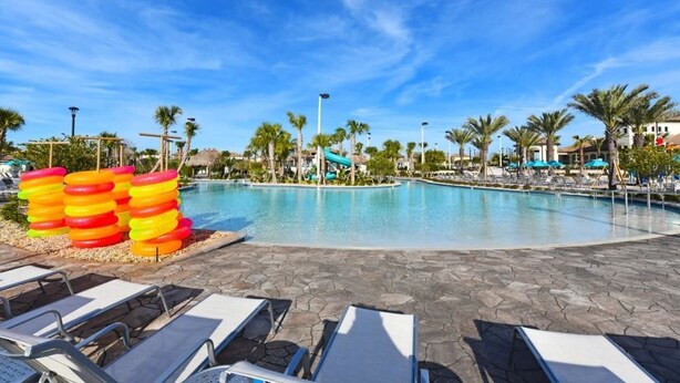 A swimming pool with lounge chairs and palm trees.