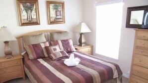 A bedroom with a bed, nightstands, a dresser, and two wall-mounted lamps. - 157 Sandy Ridge House 5 Bedroom by Florida Star (Davenport)