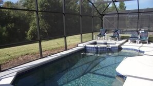 A swimming pool with a hot tub, surrounded by a covered area with chairs. - 157 Sandy Ridge House 5 Bedroom by Florida Star (Davenport)