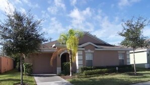 A residential house with a front porch, a garage, and a well-maintained lawn. - 157 Sandy Ridge House 5 Bedroom by Florida Star (Davenport)