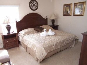 A neatly made bed with a patterned bedspread, a wooden headboard, a bedside lamp, and a small nightstand with drawers.