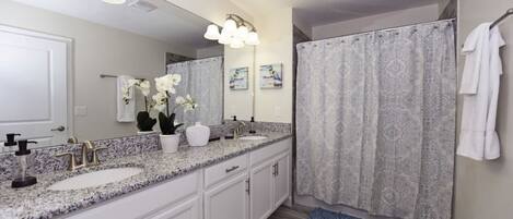 A bathroom with two sinks, a large mirror, and a shower curtain.