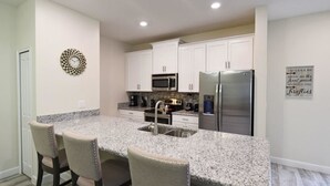 A modern kitchen with white cabinets, stainless steel appliances, and a granite countertop.