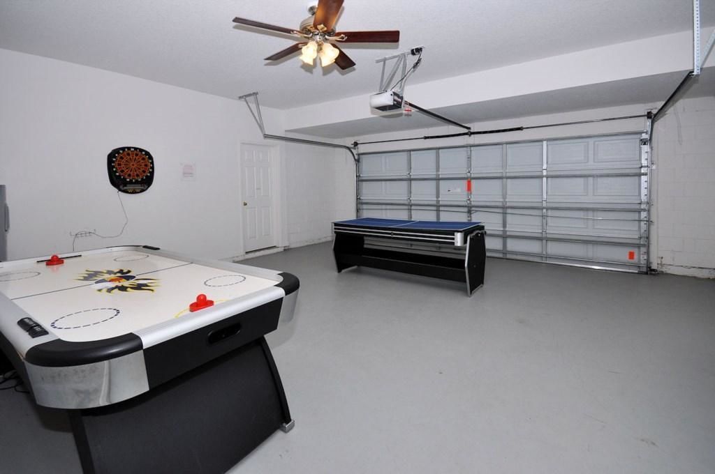 A room with a foosball table, a dartboard, and a ceiling fan.