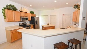 Una cocina moderna con armarios de madera, una isla central y taburetes de bar.
