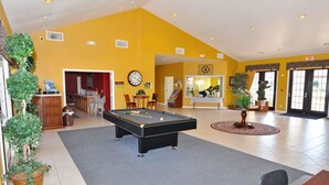 A pool table in a room with yellow walls, a clock, and a door leading to another room. - 16708 High Grove House 4 Bedroom by Florida Star (Clermont)