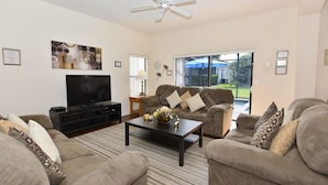 A living room with a flat-screen TV, two sofas, a coffee table, and a ceiling fan. - 16718 High Grove House 4 Bedroom by Florida Star (Clermont)