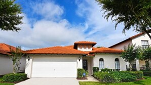 A two-story house with a red-tiled roof, a white garage door, and a well-maintained lawn. - 16805 High Grove House 4 Bedroom by Florida Star (Clermont)