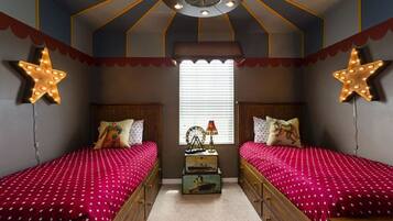 A bedroom with two beds, star-shaped wall lights, a ceiling fan, and a window with blinds.