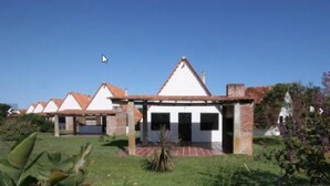 Una hilera de edificios blancos con tejados de tejas rojas, rodeados de follaje.