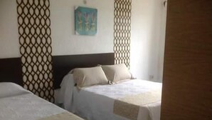 Habitación de hotel con dos camas, cabecero de madera y un panel decorativo en la pared.
