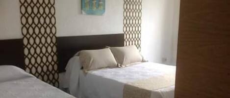 Une chambre d’hôtel avec deux lits, une tête de lit en bois et un panneau décoratif mural.
