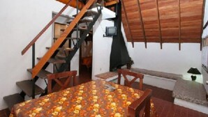 Un comedor con una mesa y sillas, una escalera y un techo de madera.