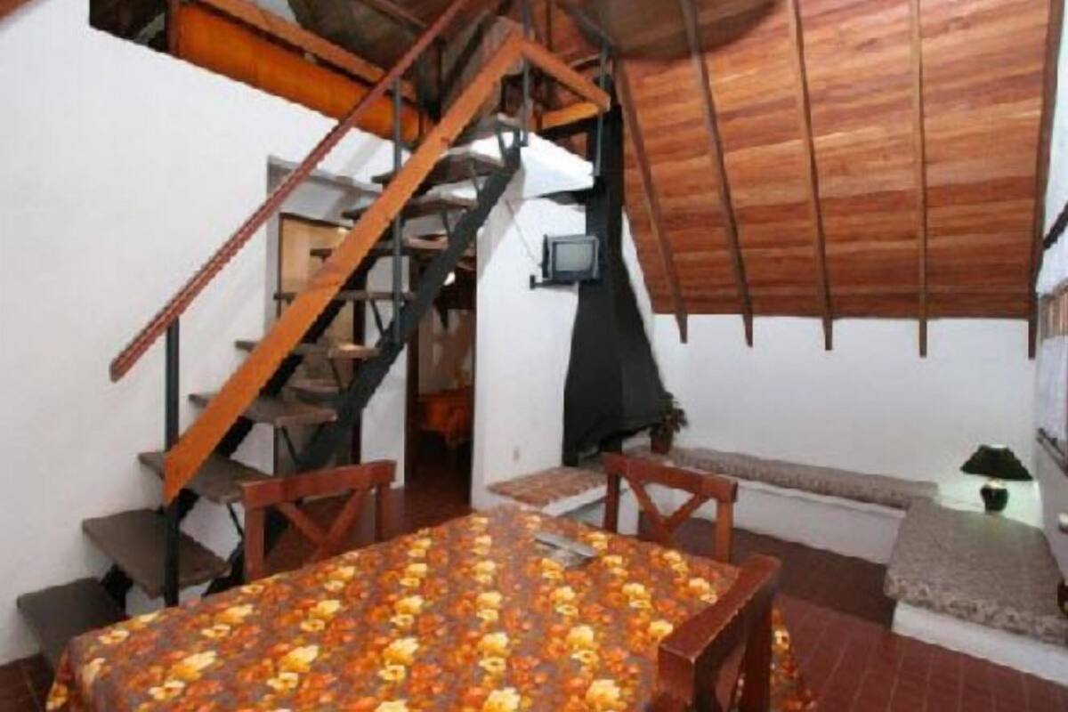 Un comedor con una mesa y sillas, una escalera y un techo de madera.