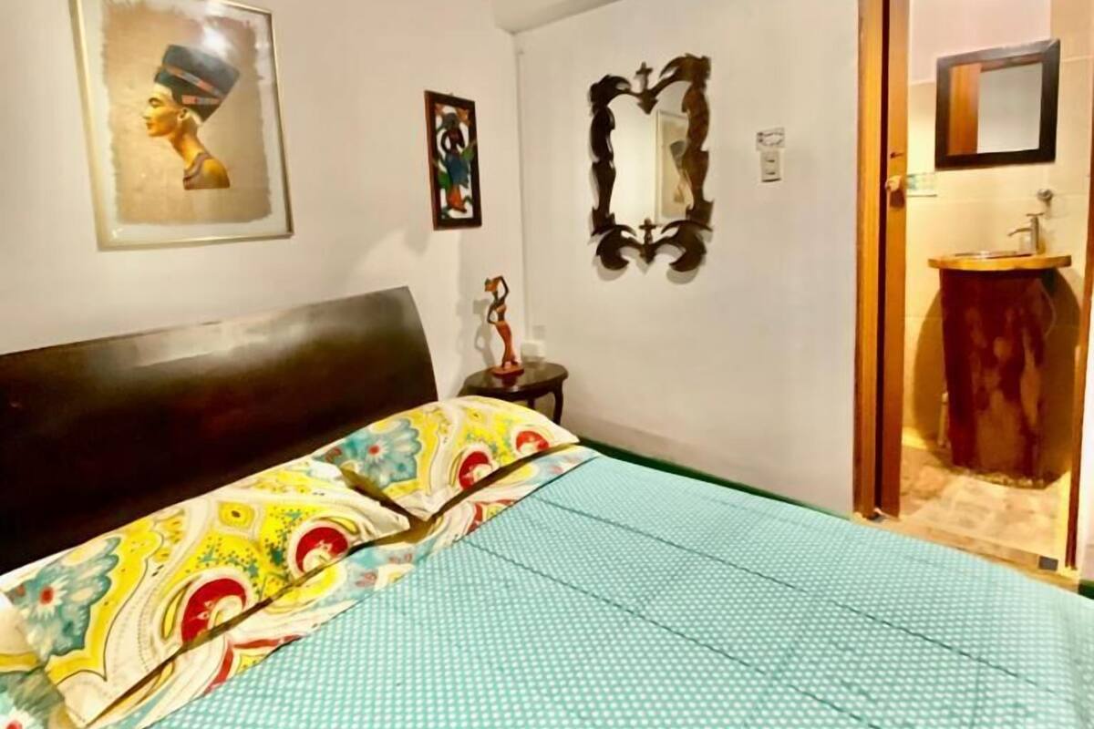 Une chambre à coucher avec un lit, un miroir et des œuvres d’art accrochées aux murs.