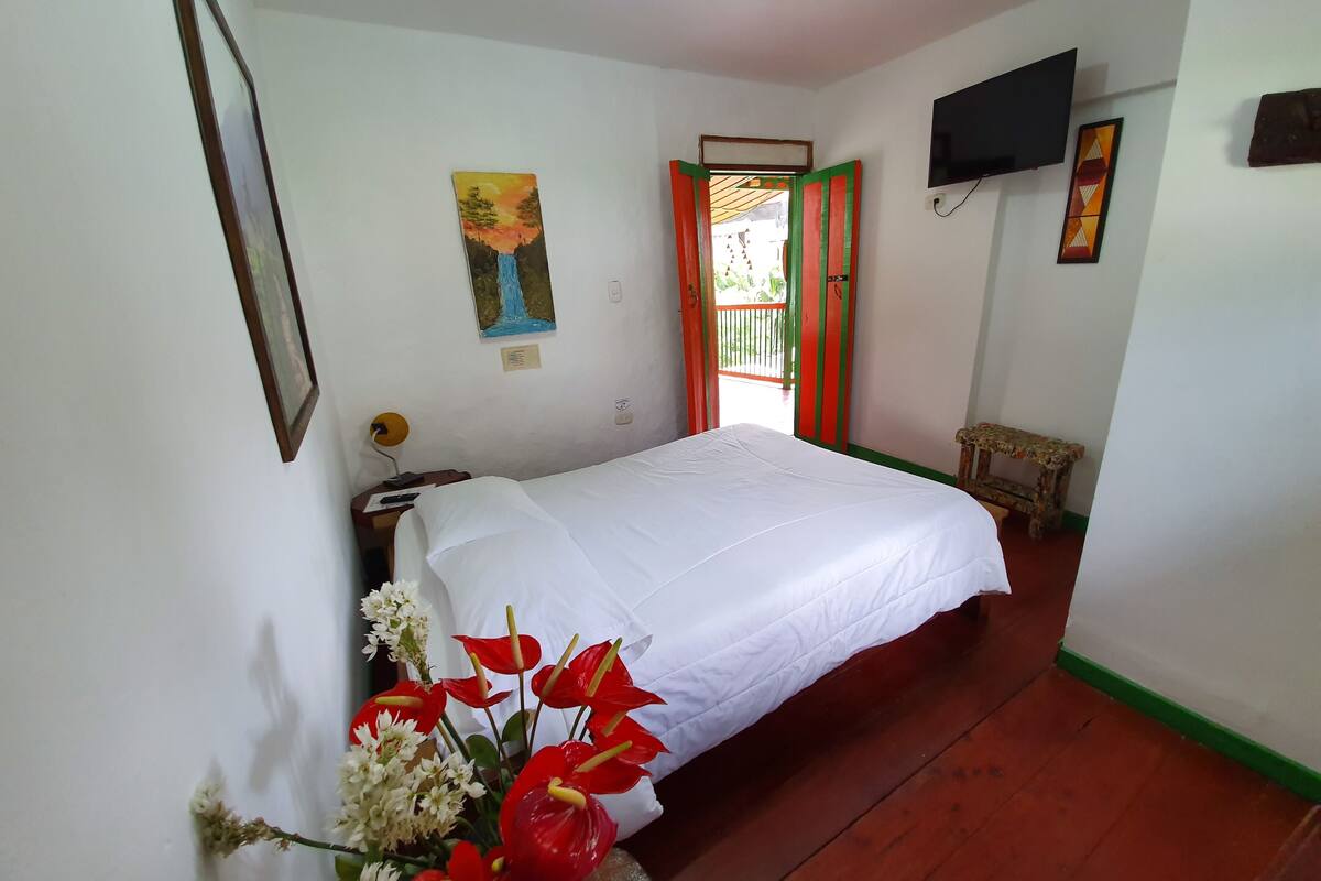 Une chambre avec un lit, un tableau, une télévision et une fenêtre donnant sur un beau paysage.