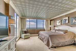 A spacious bedroom with a large bed, a television, and a view of the ocean.